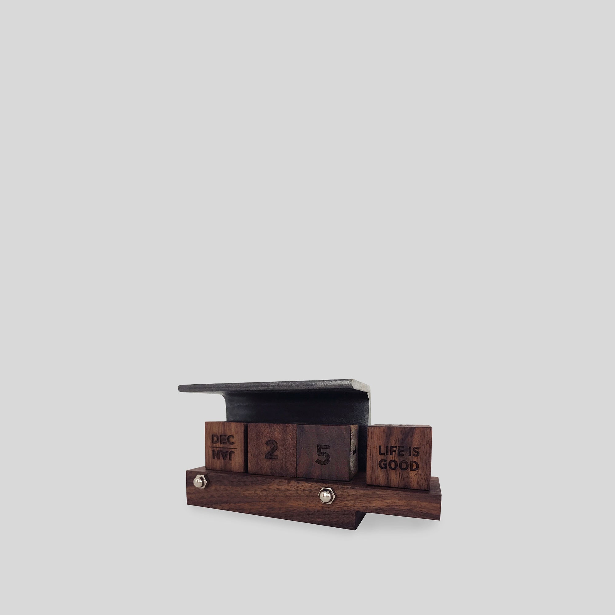 Perpetual Calendar Ferro with wooden cubes displaying numbers, mounted on a steel angle, featuring a wooden ledge for business cards.