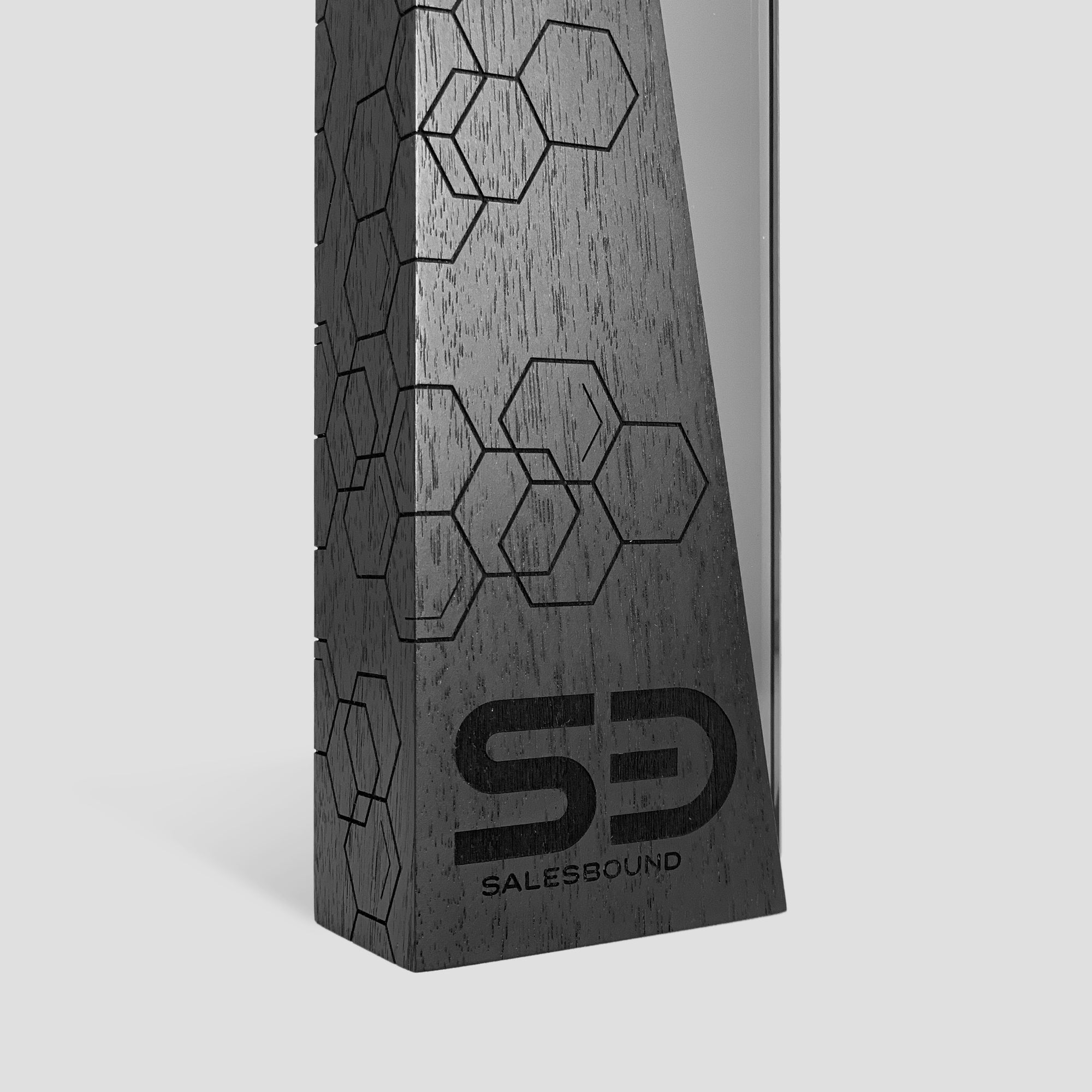 DI/MI Wood Award: Close-up of ebony-stained wood featuring interlocking wood and glass trophy design elements that symbolize collaboration and creativity in a modern, sophisticated form, engraved for sales award trophies.