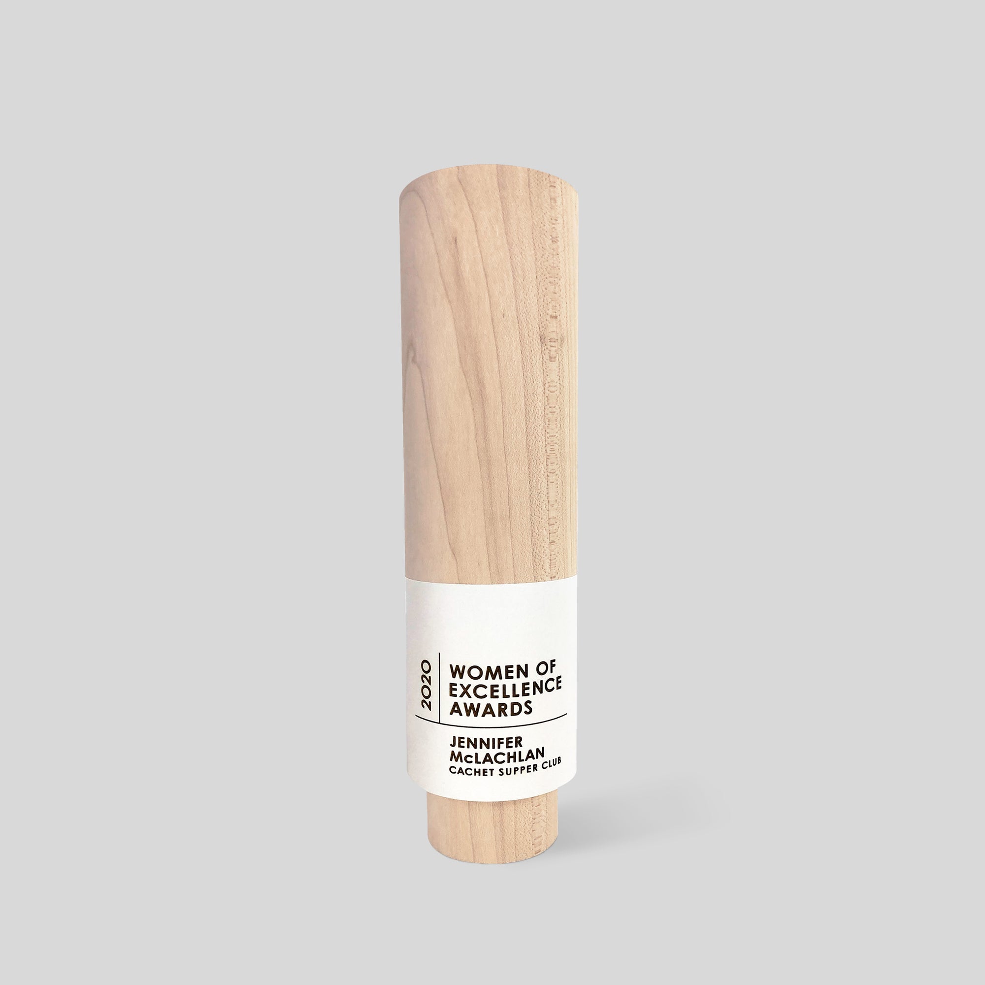 Geometria Award Circulus: a wood cylinder trophy with a white nameplate that is laser engraved and personalized, showcasing minimalist design and natural wood grain, symbolizing unity and achievement. Architect-designed and artisan-crafted in the USA.