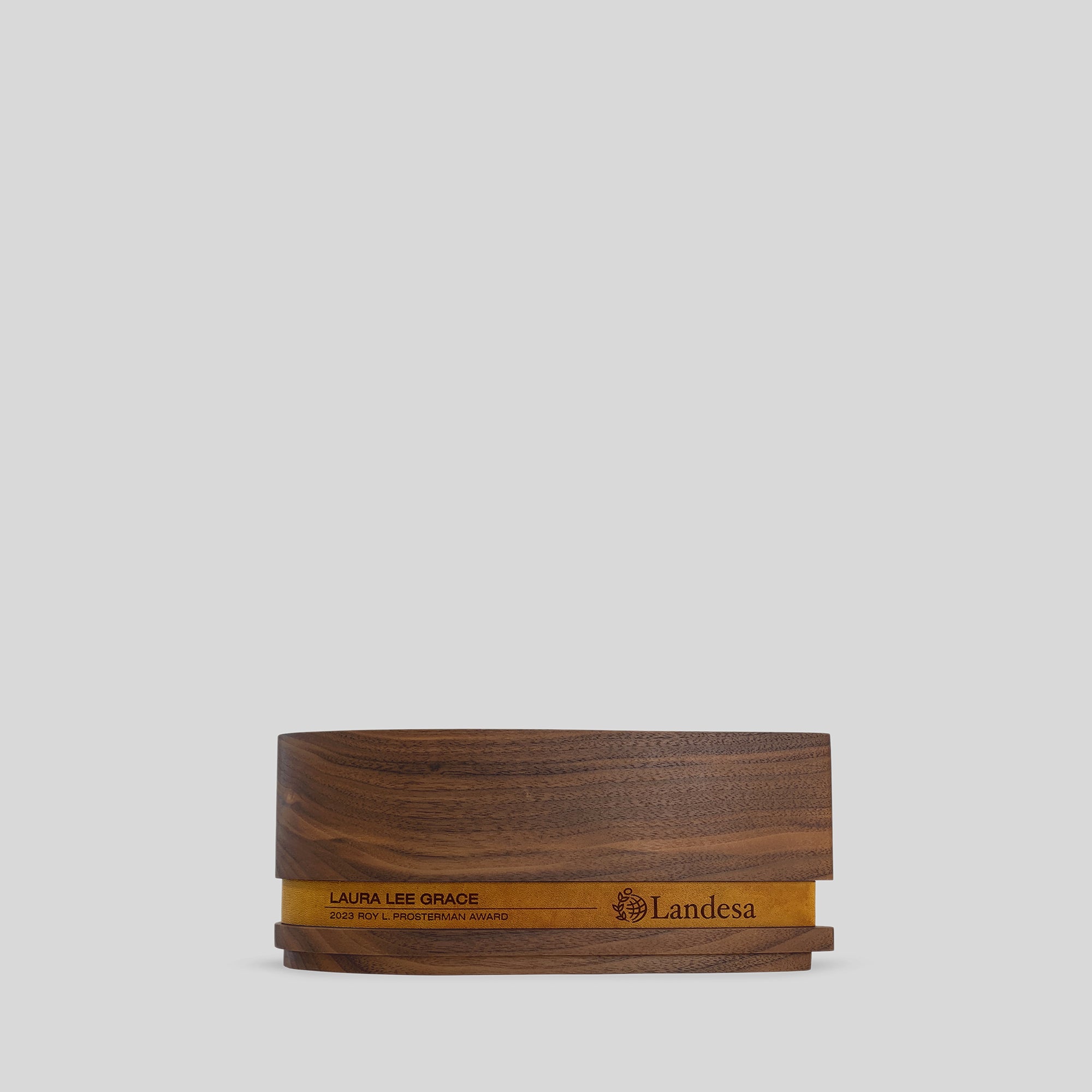 Ovali Award: A wooden box displaying a logo, symbolizing harmony and progress, crafted from smooth walnut with a sophisticated leather band.