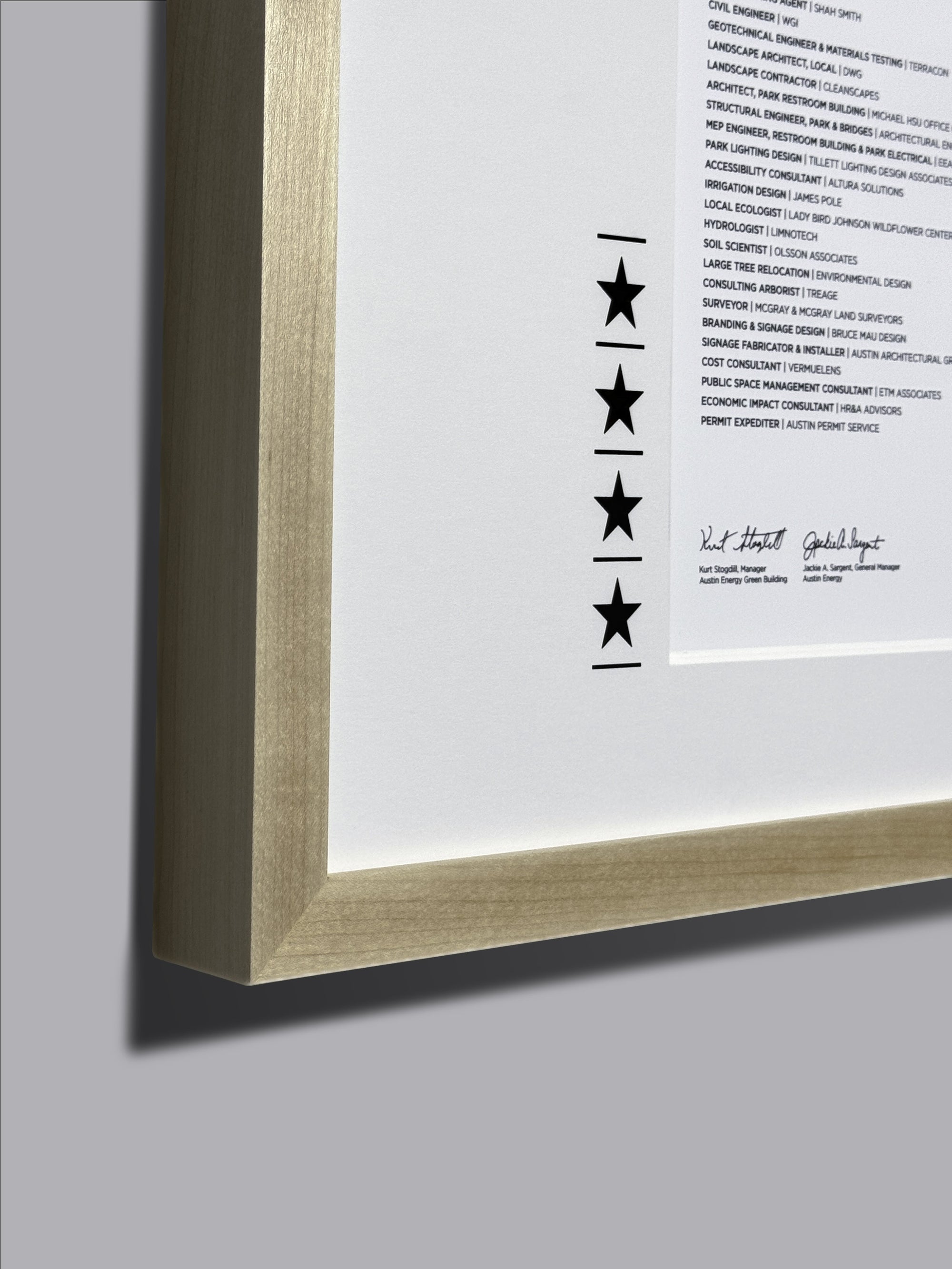 Maple frame with black stars on a white background, showcasing a certificate display, emphasizing the frame&#39;s close-up details and wood texture.