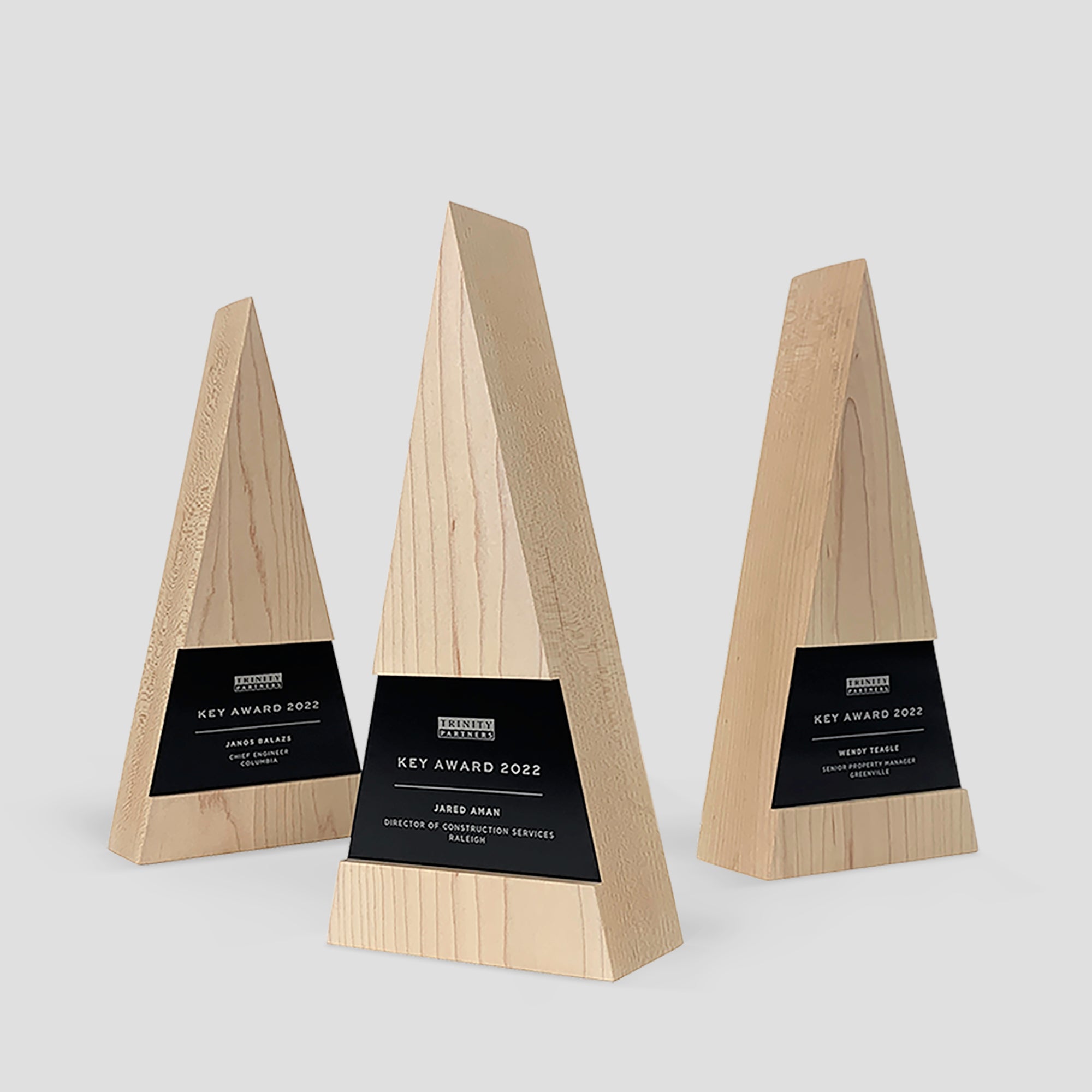 Figura Trigonum Award: Wooden trophy with triangular shape, expertly crafted from maple wood with engraved personalization on black metal nameplates. Personalized for annual employee recognition awards. 