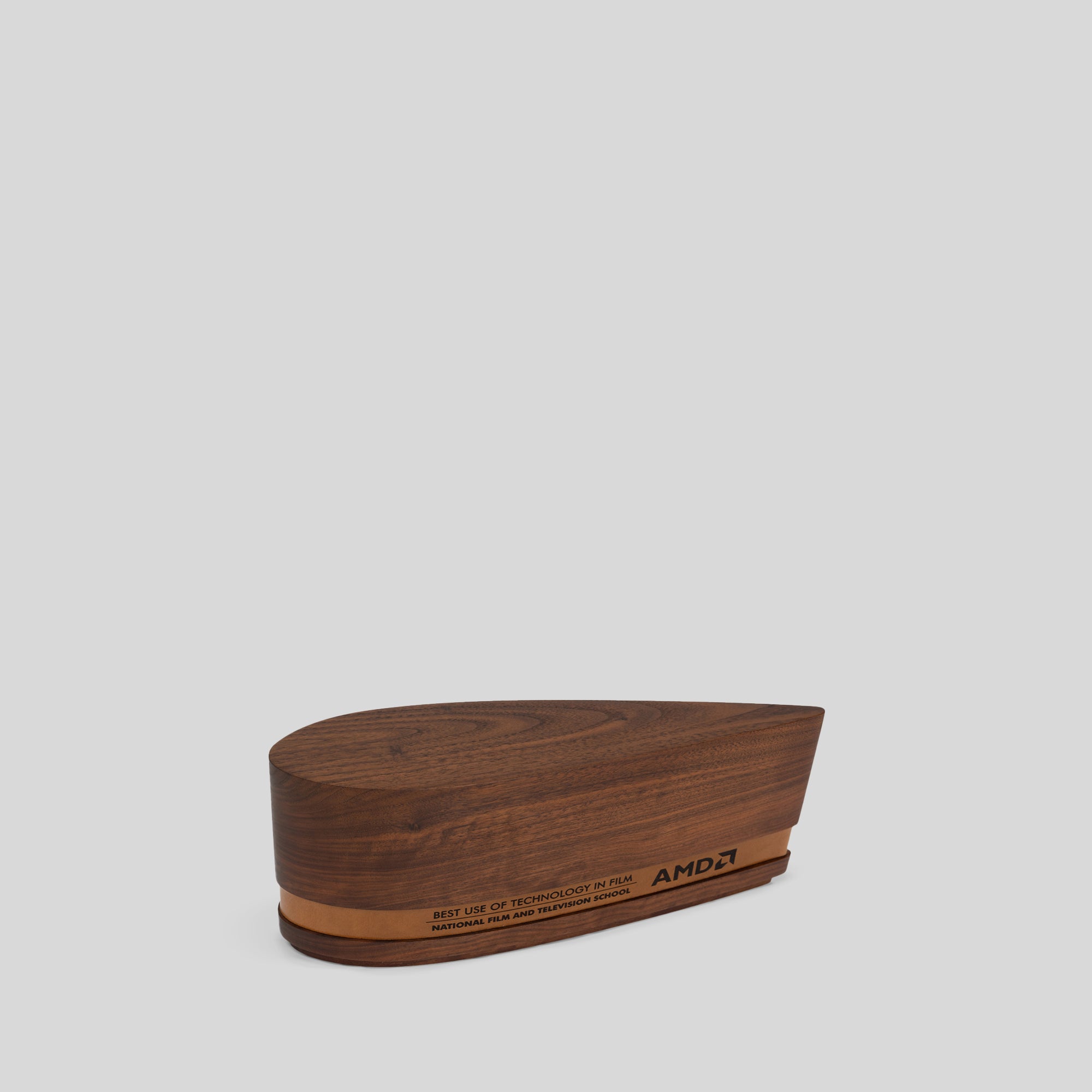 Ovali Award, a walnut wooden box with engraved text and logo, featuring a leather band, highlighting natural wood grain and craftsmanship.